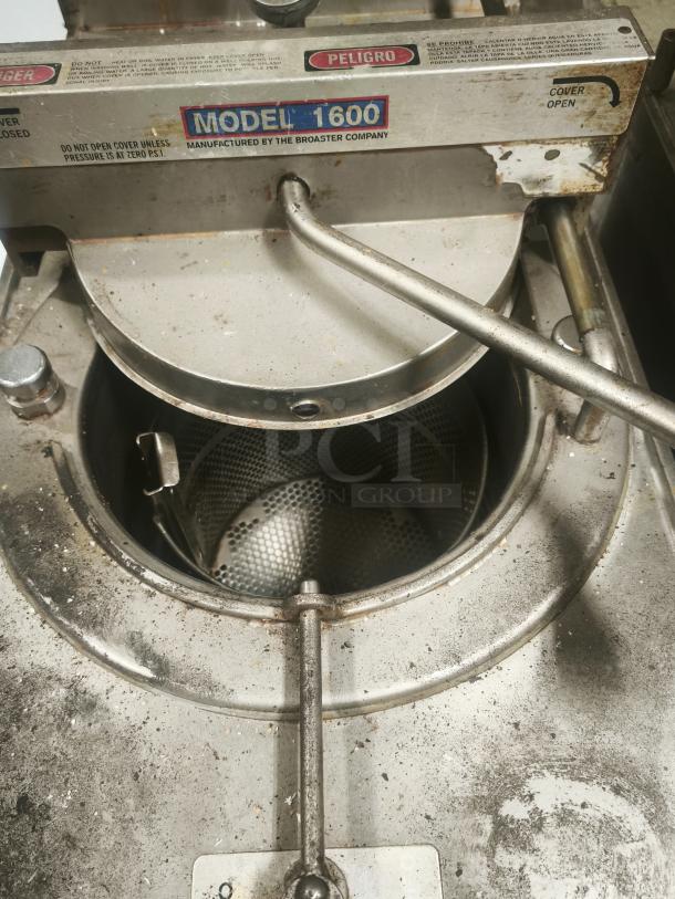 BroasterFryer Model 1600 pressure fryer, stainless steel, visible wear, "PELIGRO" safety label, lid partially open.