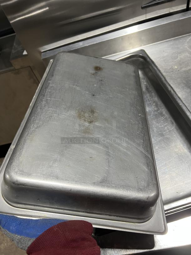 Stainless steel stackable steam table pan with visible wear and discoloration. Ideal for commercial use.