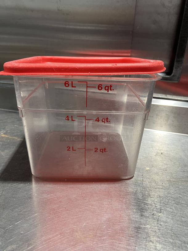 Commercial clear polycarbonate 6 qt food storage container with red lid and measurement markings.