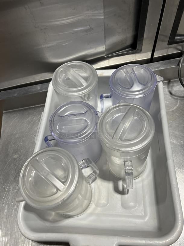 Clear polycarbonate beverage pitchers with lids, in a tray. Durable material, commercial quality, excellent condition.