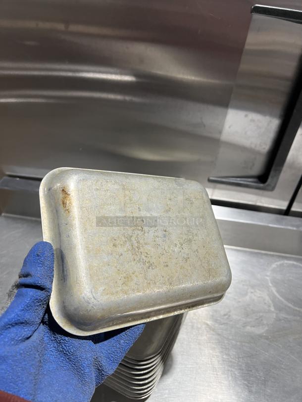 Commercial aluminum baking pan, used condition, stack shown. Rugged surface, suitable for high-volume cooking.
