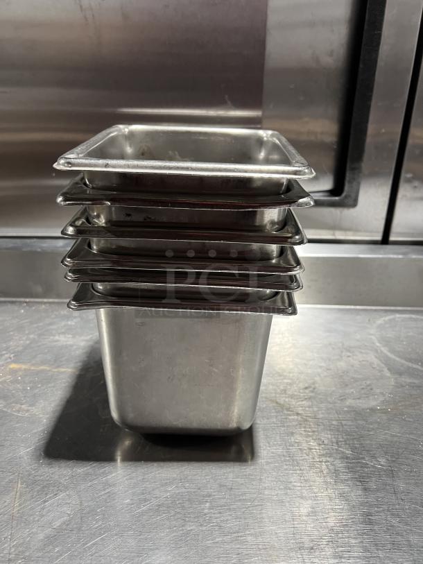 Stack of commercial stainless steel steam table pans, good condition, set of six, ideal for catering or foodservice use.