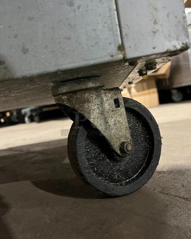 Bottom caster wheel of a Beverage Air HF2-1S commercial refrigerator, showing wear, part of a stainless steel frame.