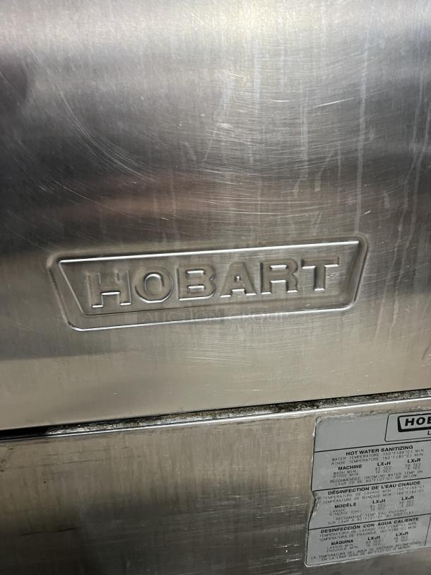Hobart LXe Series commercial stainless steel undercounter dishwasher, featuring visible branding and usage instructions.