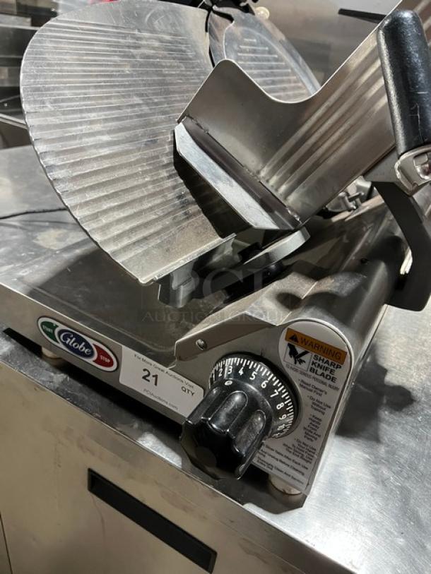 Globe electric deli slicer, commercial-grade. Features sharp blade, adjustable thickness dial, and warning label. Good condition.