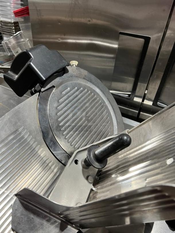 Globe countertop electric meat deli slicer, shown with power features, on support legs, stainless steel, in used condition.