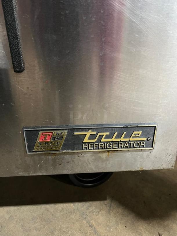 True TSSU-60-16D-4 stainless steel refrigerated prep table, four drawers, cutting board, casters, model label visible.