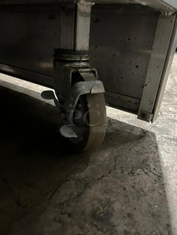 Atlas Metal WIHDM4 steamtable caster wheel; commercial-grade, stainless steel, shows wear, part of mobile hot food unit.