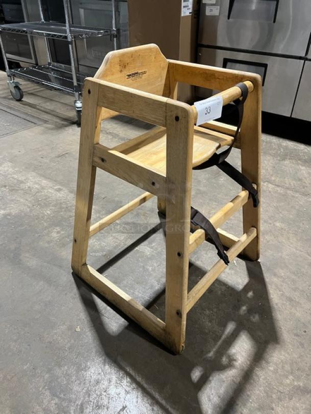 Commercial wooden highchair with safety strap, natural finish, sturdy construction, and visible product branding.