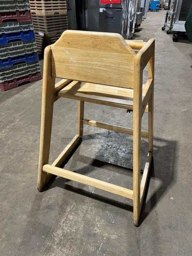 Commercial wooden highchair with safety strap, natural finish, minor wear, sturdy design. Ideal for restaurant use.