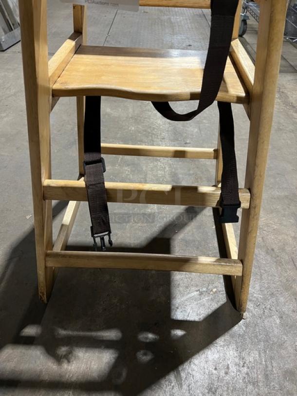 Commercial wooden high chair with safety strap, solid construction, natural finish, ideal for restaurant use, good condition.