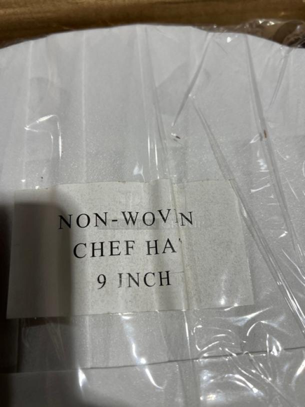 NEW Landau Uniforms white non-woven 9" round chef hat with label indicating "NON-WOVEN CHEF HAT 9 INCH," in original packaging.
