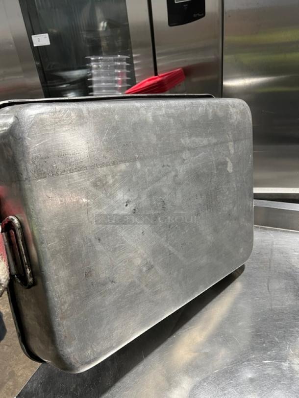Commercial rectangular roasting pan with handles, metal construction, used condition, visible wear and scratches.