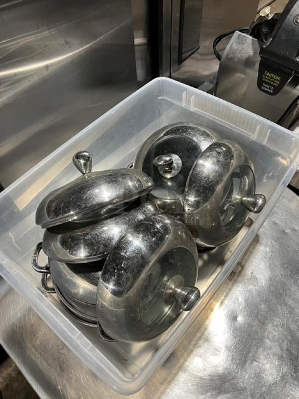 Round braiser pans with dome-style lids, stainless steel, used condition, multiple units in a storage bin.