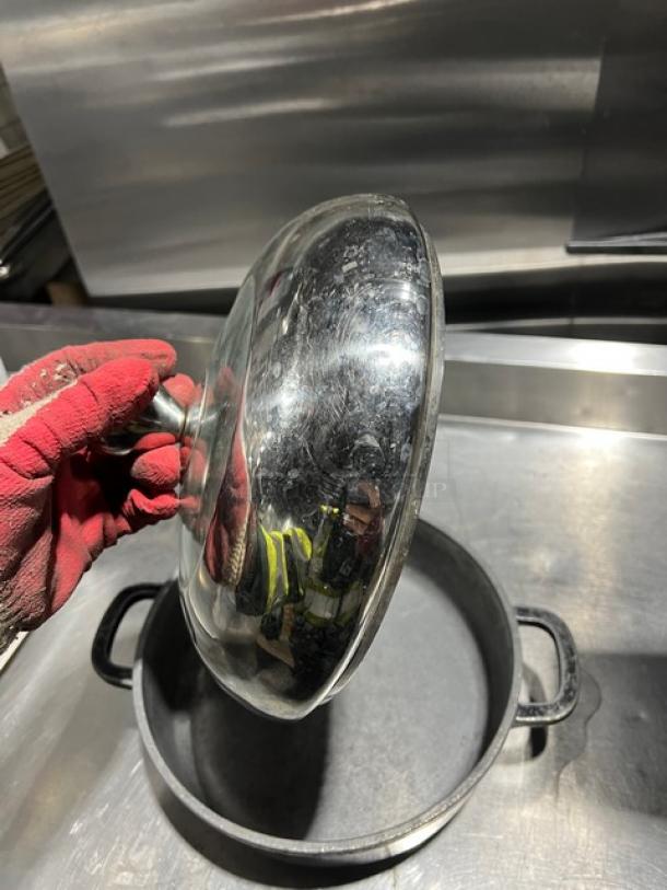 Commercial round braiser pan with dome lid, metal handles, slightly worn condition, ideal for bulk cooking.