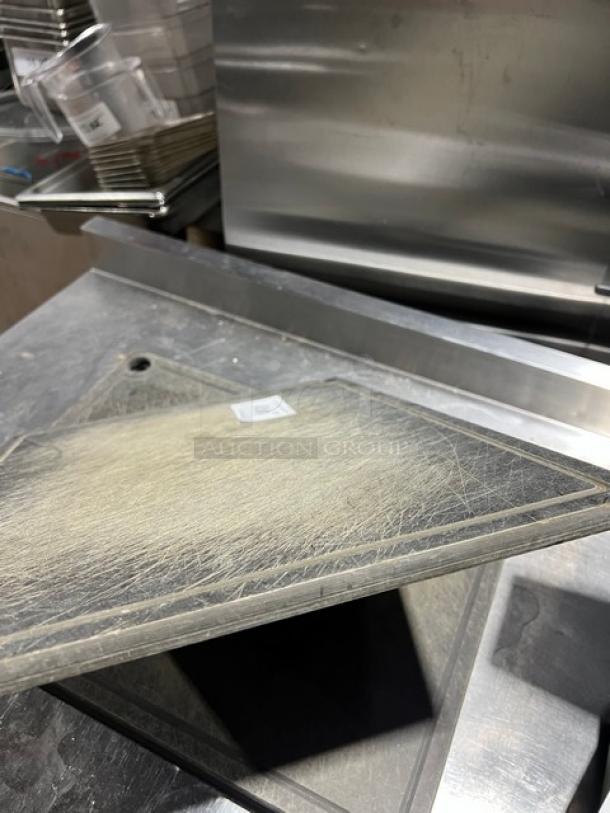 Commercial rectangular cutting board, worn condition with visible scratches. Features mounting hole and visible label.
