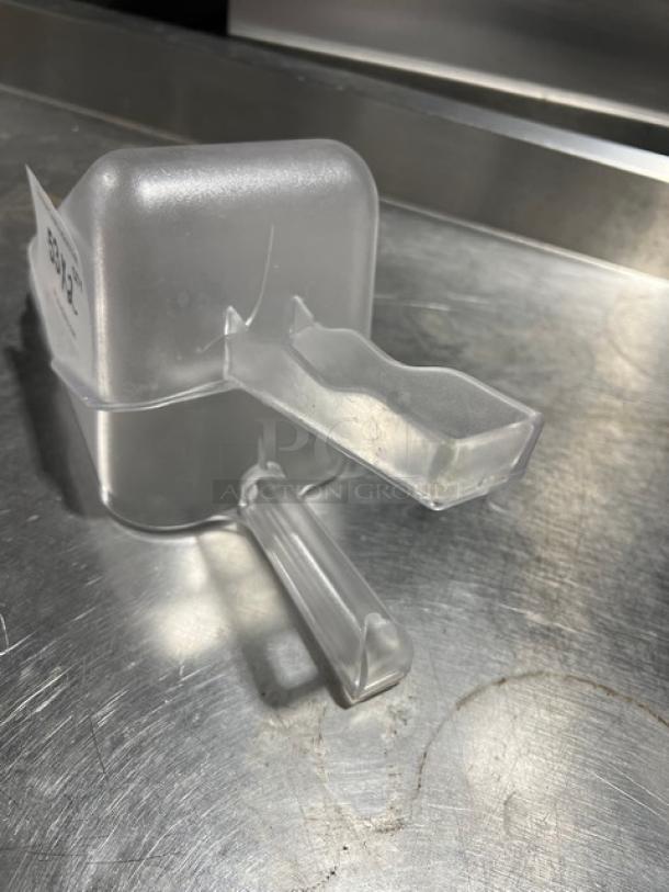 Clear handheld scoop with ergonomic handle and rectangular base. Good condition, ideal for commercial use.