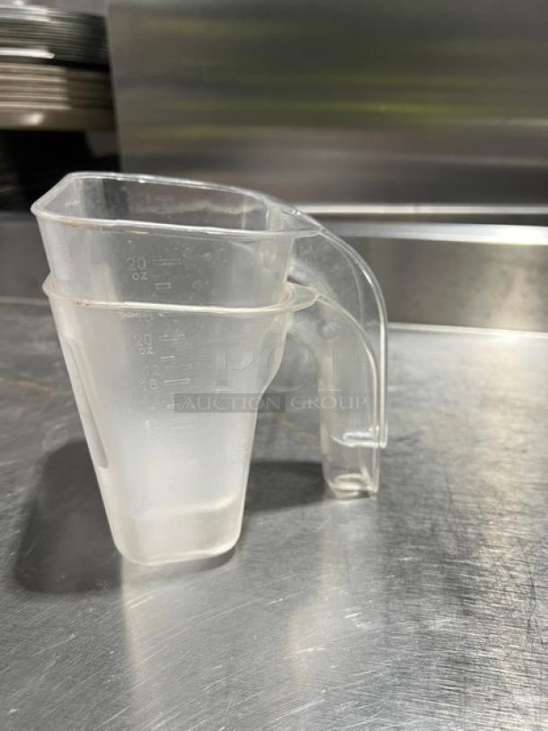 Clear 20 oz. handheld measuring cup with marked measurements on the side, in used condition. Ideal for commercial use.