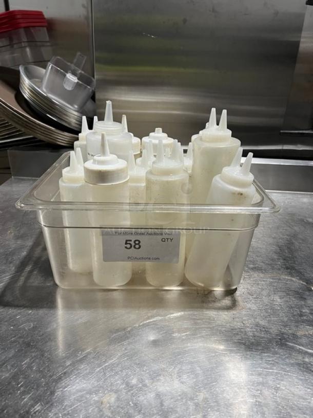 Lot of clear condiment squeeze bottles with lids in a plastic container, labeled "58" for auction, used condition.