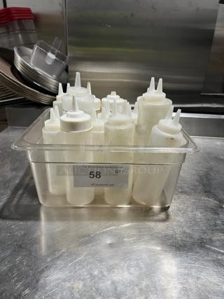 Lot of clear condiment squeeze bottles with lids in a plastic container, labeled "58" for auction, used condition.