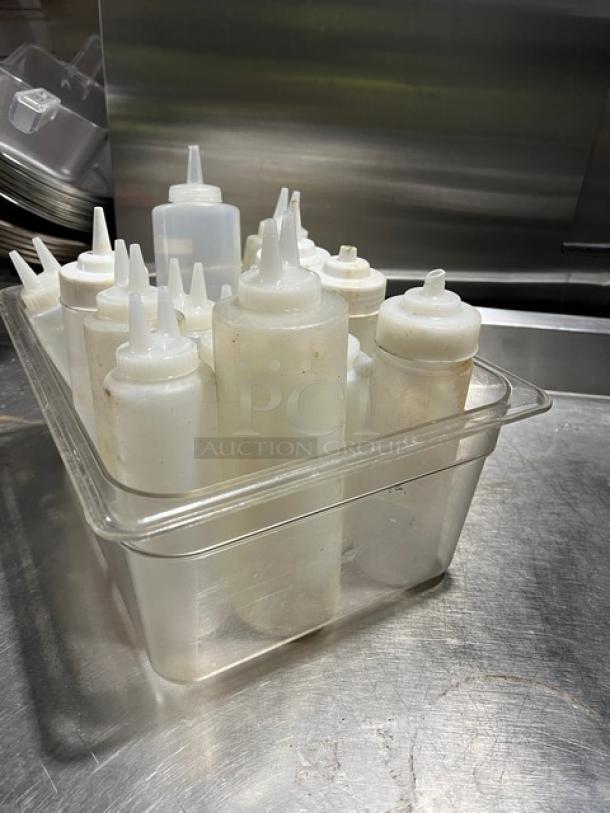 Lot of clear condiment squeeze bottles with lids in varied sizes, fair condition, ideal for sauces, sold as one unit.