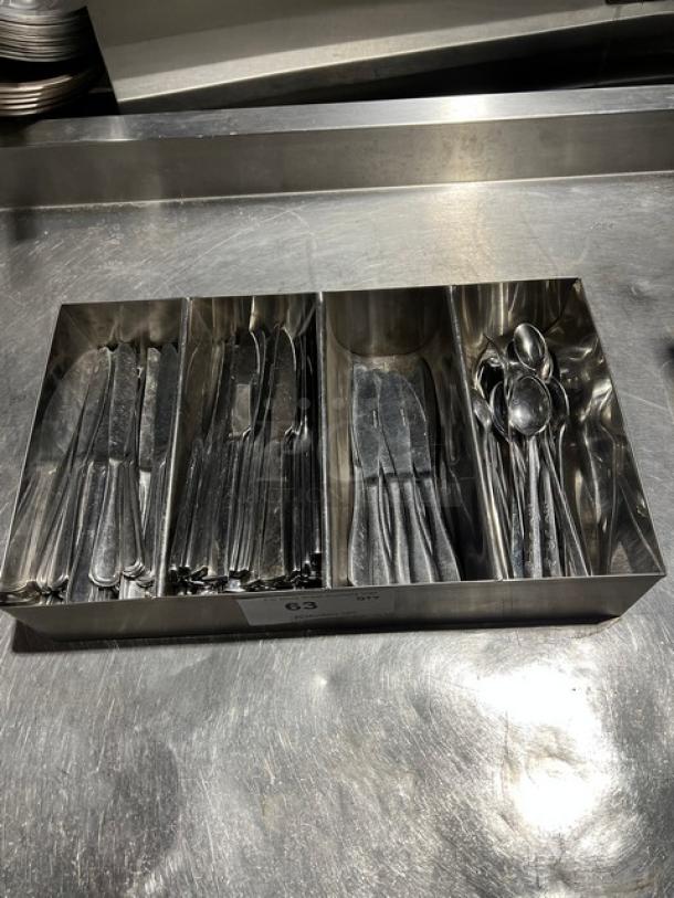 Lot of assorted knives and spoons in a 4-compartment metal organizer. Used condition, stainless steel finish.