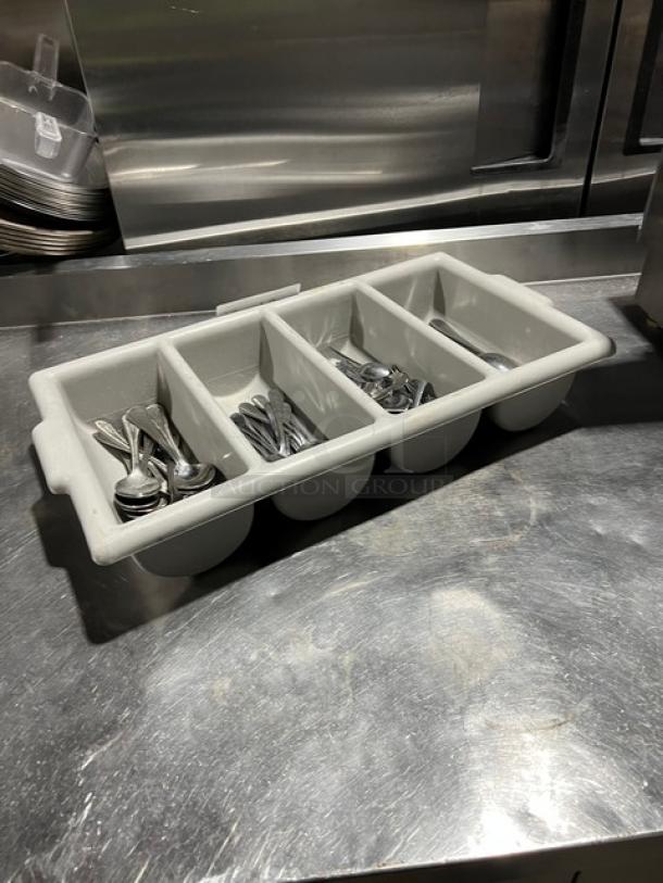 Lot of miscellaneous commercial spoons in a 4-compartment utensil organizer, excellent condition, on a metal surface.