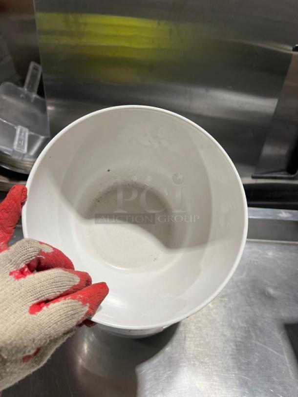 Commercial round white bowl, clean and in good condition, shown on a metal surface. Features subtle floral pattern inside.