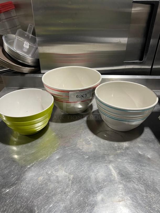 Three assorted commercial round bowls on metal surface; colors include lime green, red-striped, and blue-striped.
