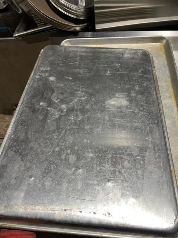 Commercial stainless steel full-size sheet pan, used condition with visible wear, ideal for baking or roasting.