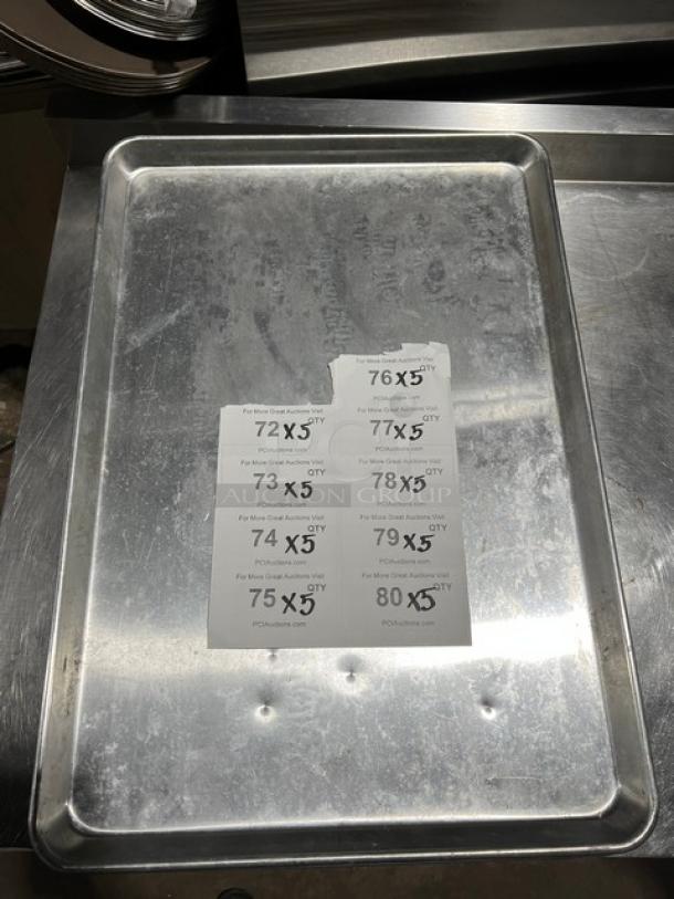 Stainless steel full-size sheet pan, commercial-grade, showing some wear, with auction lot labels attached.