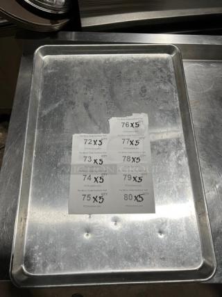Stainless steel full-size sheet pan, commercial-grade, showing some wear, with auction lot labels attached.