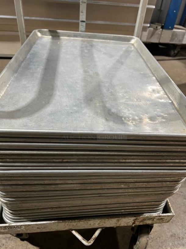 Stack of commercial stainless steel full-size sheet pans on rack, in good condition. Durable and ideal for baking use.