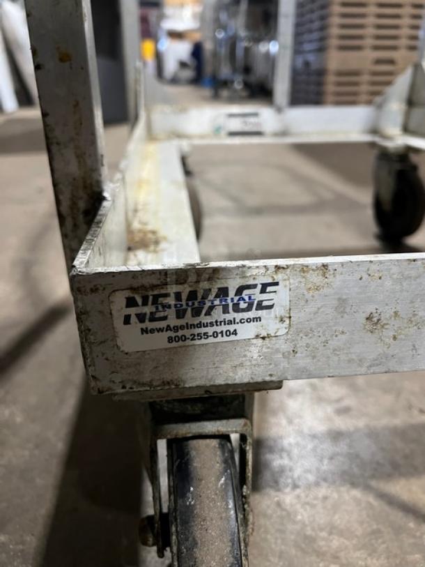 New Age Industries heavy-duty sheet pan dolly on casters, visible wear, branded label with contact info.