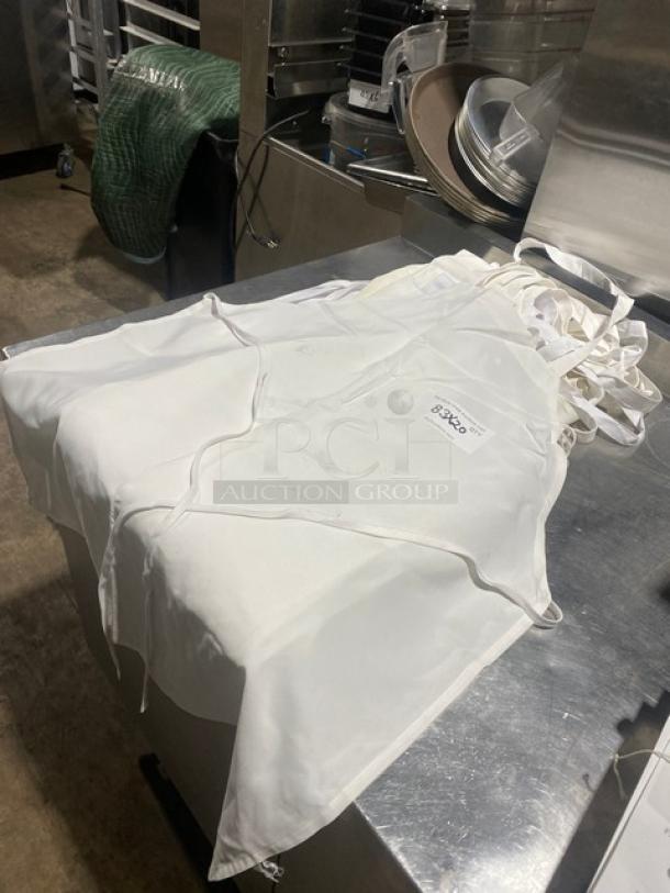 White full-length bib apron, commercial use, featuring adjustable straps. Multiple pieces shown in good condition.