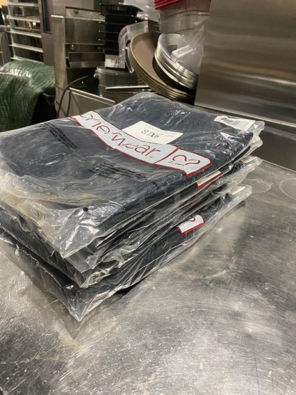 Chefwear CW3100-CW50 black medium chef pants, new in packaging, stacked on a table.