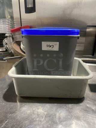 Gray commercial waste bin with blue lid, placed inside a gray utility bucket. Label shows "9QX3 QTY."