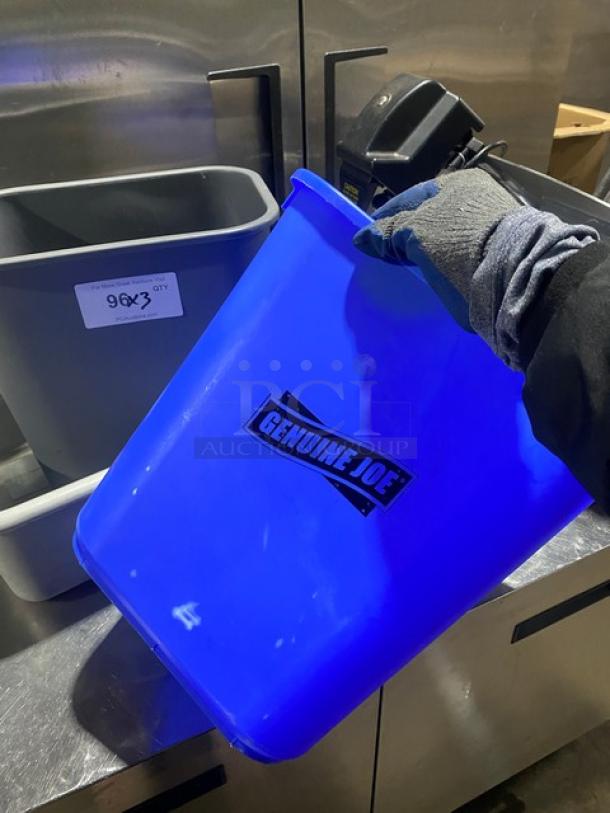 Blue Genuine Joe trash can with label, held by gloved hand. Includes utility bucket and bus box. Good condition.