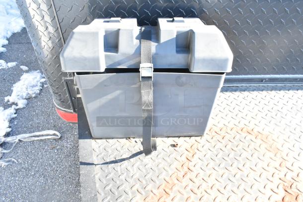 Battery box with strap attached to a diamond plate steel surface on a Southern Dimensions food trailer.