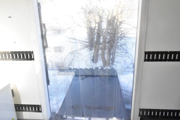 Interior of a Southern Dimensions food trailer, featuring metal panels and a clear strip curtain door. Ready for customization.