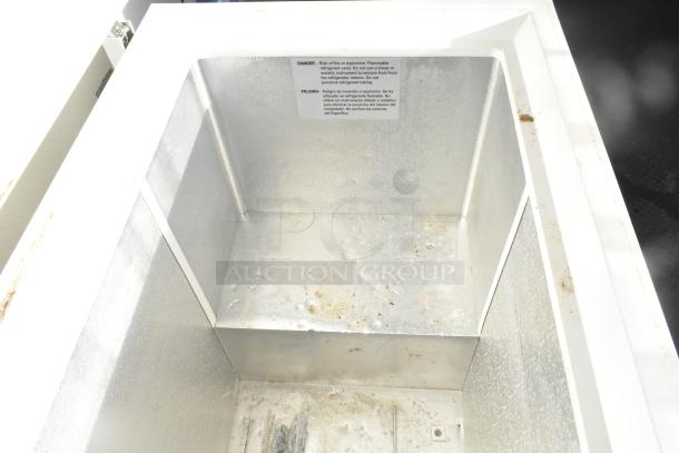 Interior of Kenmore chest freezer inside Southern Dimensions shell food trailer, showing metal lining and safety label.