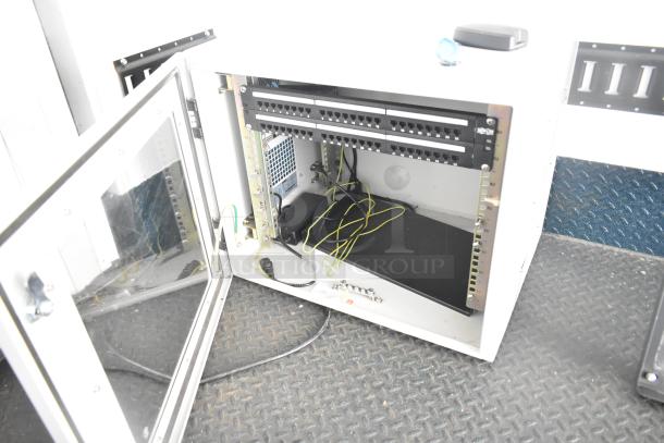 Open server cabinet with wiring and patch panels on non-slip flooring. Suitable for tech integration in a food trailer.