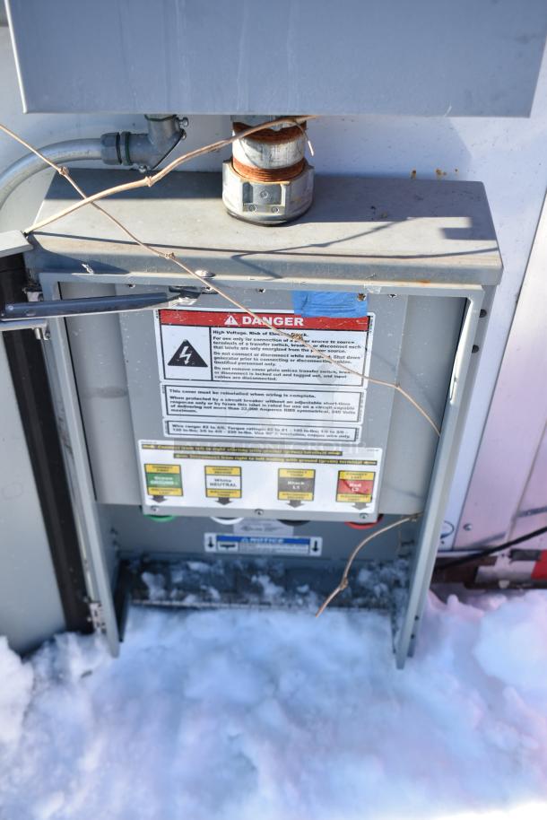 Electrical panel on snow-covered ground with visible wiring. "Danger" label warns of high voltage risk.