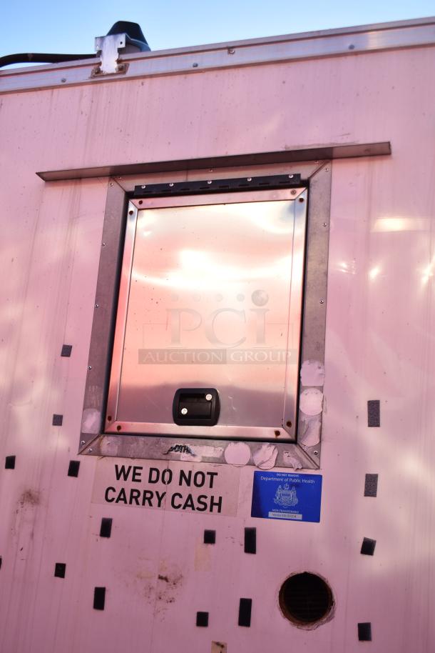 ATX 28' food trailer window with a "We Do Not Carry Cash" sign and Department of Public Health sticker.