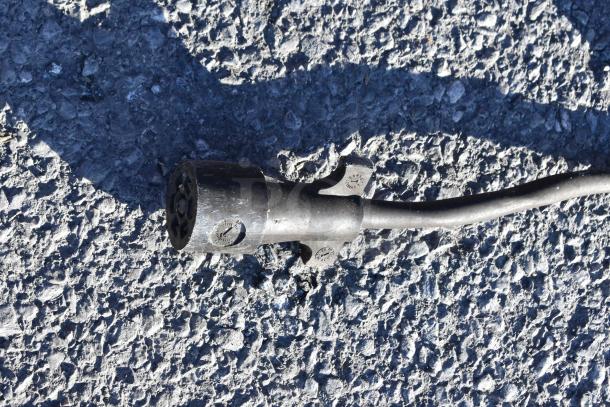 A black electrical plug or connector on a textured asphalt surface.