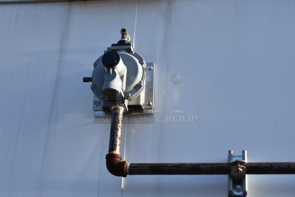 Rusted metal gas regulator and pipe mounted on the exterior wall of the ATX 28' trailer.