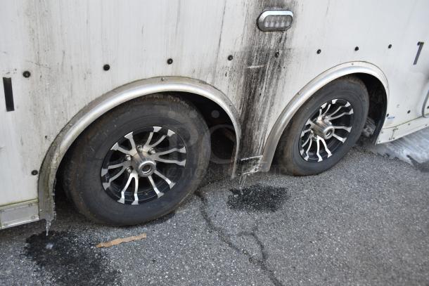 Dual tire setup on an ATX 28' unbranded cold food and beverage trailer, showing signs of wear.