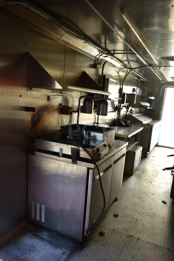 Interior of an ATX 28' unbranded food trailer with commercial-grade equipment, including Arctic Air prep tables and coolers.