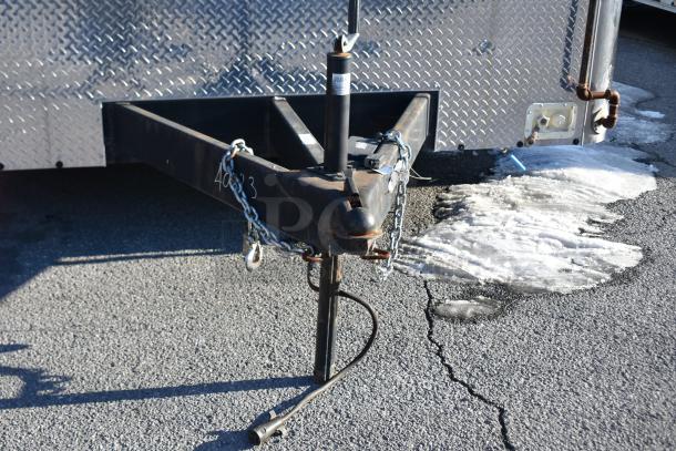 ATX 28' unbranded trailer hitch on asphalt, chains attached, snow nearby. Visible metal diamond plate exterior.