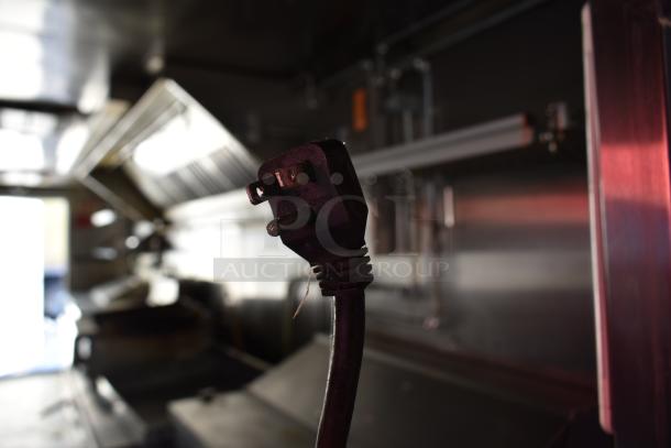 ATX 28' food trailer interior with grease hood and power plug, equipped with Arctic Air appliances and charbroiler.